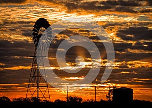 Wind driven water pump silhouette at sunset