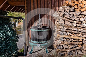 Old fashioned wine press next to pile of logs