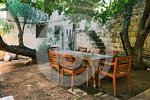 Old-fashioned wooden dining table and chairs outside in a Mediterranean garden