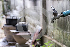 Old faucet with water leaking drop to the ground