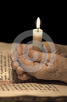 Old female hands with a candle