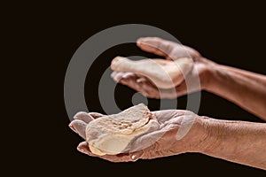 Old female hands holding a brown loaf of bread. Helping hand sharing bread. Man giving bread, Helping hand concept. A