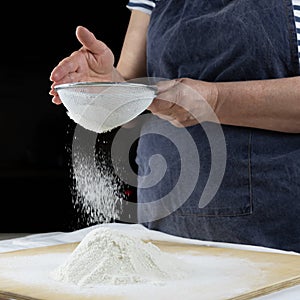 Old female hands sift flour
