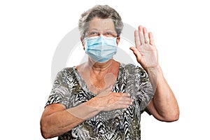 Old female model making honest oath gesture wearing surgical mask