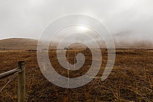 An old fence crosses a dreary, foggy, empty, and barren winter landscape at the National Bison Range wildlife refuge, Montana, USA