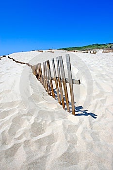 Old fence sticking out of deserted sandy beach dunes