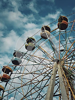 Old ferris wheel over sky background in an abandoned amusement park. Dark scene, ghost and empty carousel with no people for