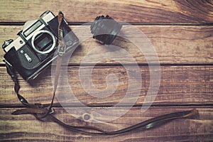 Old film camera with strap and lens on wooden background. Vintage toned and top view with free space