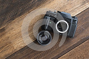 Old film DSLR camera with lens on a wooden table