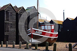 Old fisher boat on the beach of Hastings with fisher huts in the background