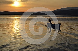 An old fisherman on the lake at sunrise