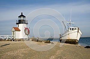 Old fishing boat aground next to a lighthouse at Christmas time photo