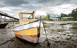Old fishing boat is moored on beach at low tide.