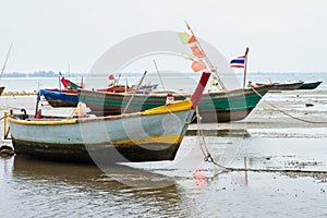 An old fishing boat moored beached on the beach at low tide.