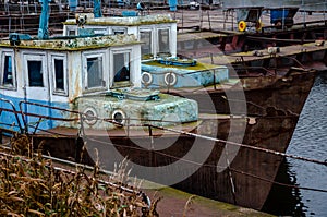 Old fishing boat moored at the pier. Rusty iron ship. Dump on the river or other reservoir. Used and abandoned fishery equipment