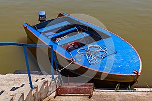 An old fishing boat is moored to the concrete embankment of the river. Background with copy space