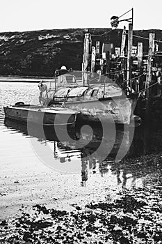 An old fishing boat is moored on the water. Black and white photo. Dramatic landscape.