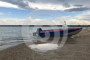 Old  fishing boat with motor stand abandoned on sea shore,