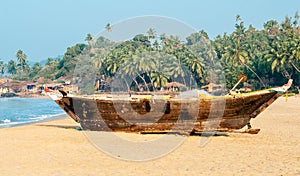 Old fishing boat on the sandy shore. In Goa