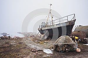 Old fishing boat stands to be repaired on a foggy morning