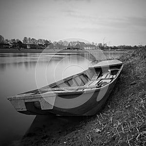 An old fishing boat stranded on the bank of the Sava River in Bosanski Brod, Bosnia and Herzegovina. Black and white picture of a