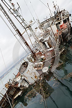 An old fishing boat sunk at a pier in seaport