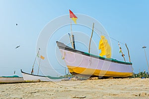 old fishing boats in the sand on the ocean in India on blue sky background