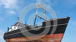 Old fishing cutter ashore with blue cloudy sky