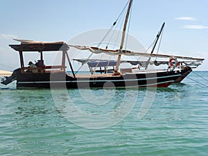 An old fishing schooner with an anchor in the water stands in the sea against the background of the sky and turquoise water