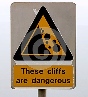 Old Flaking Dangerous Cliffs Warning Sign at a Coastal Location