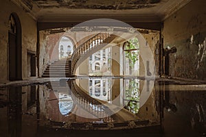 Old flooded abandoned mansion with spiral stair, water reflection