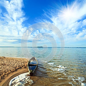 Old flooding boat on summer lake shore