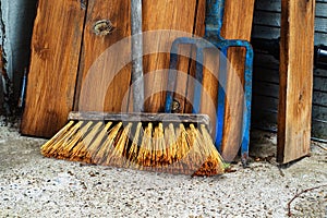 An old floor brush and metal pitchfork are located in the utility room. Antique tools for household needs. Close-up