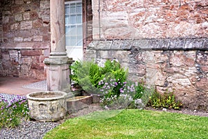 Old flower pots, flowers and ferns by a stone wall of a house