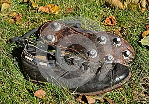 Old football shoes with cleats laying in the leaves