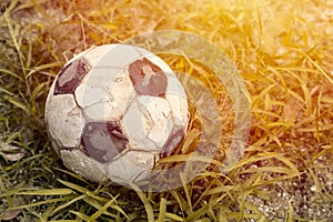 Old football or soccer ball on the grass field with sunshine space for text