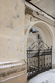 Old forged black iron gate. Details architecture of enter in arch medieval building.