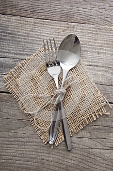 Old fork and spoon on a wooden table napkin and burlap, grunge rustic style, top view