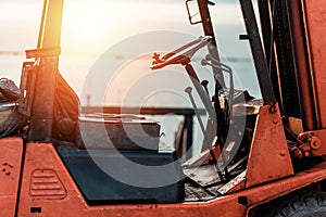Old Forklift transporting cargo on a road near the sea with sunset time