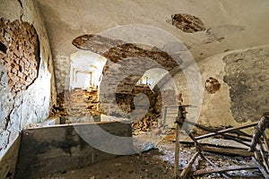 Old forsaken empty basement room of ancient building or palace with cracked plastered brick walls, low arched ceiling, small