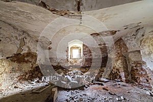 Old forsaken empty basement room of ancient building or palace with cracked plastered brick walls, low arched ceiling, small