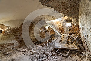 Old forsaken empty basement room of ancient building or palace with cracked plastered brick walls, low ceiling, small windows with