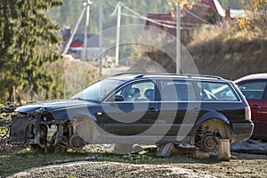 Old forsaken rusty broken trash car after crash accident without wheels on wood stamps covered with snow on winter day outdoors