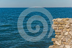 Old fortress in the rocks above the sea. Rocky cliff in the ancient at the top. Stone boulders sticking out of the