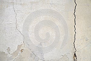 Old foundation and plaster wall with cracks. Building requiring repair closeup.