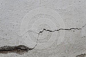 Old foundation and plaster wall with cracks. Building requiring repair closeup.