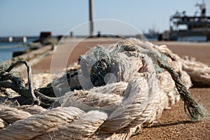 Old frayed rope in a pile on the fishing dock, Close up, shallow depth of field.