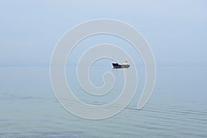 Old freighter on roadstead, calm sea, hazy day, no horizon between water and sky