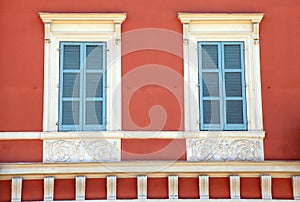 Old french blue shutter windows in red house, Nice, France.