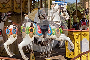 Old French carousel in a holiday park during sunny day. Horses on a traditional fairground vintage carousel. Merry-go-round with